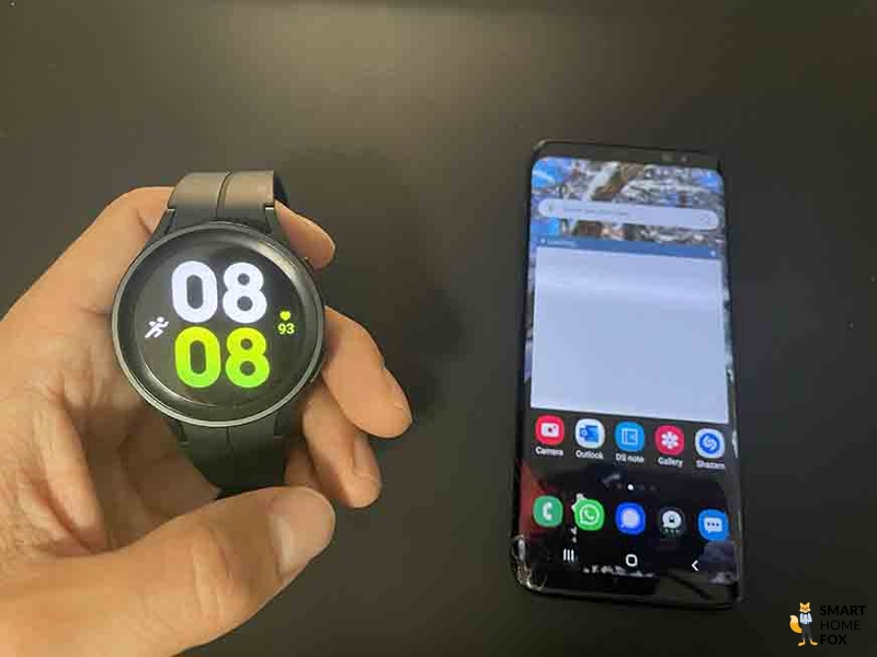 Galaxy Watch 5 рядом с мобильным телефоном.